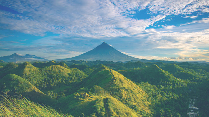 image of a landscape of green mountains and blue sky with clouds